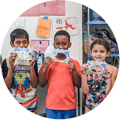 3 kids holding up artwork they made during Camp H2O